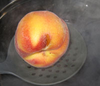 We dip the peaches into boiling (simmering) water, we put in about 6 peaches at a time for approximately 1 minute, then immediately remove the peaches and put them in cold water to cool the peaches down, or you will cook them.